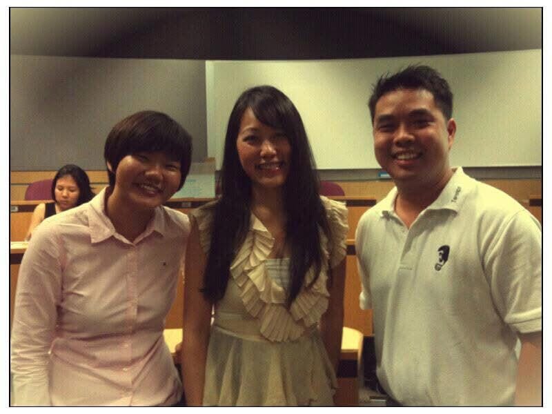 Three people smiling in a university lecture theatre after a design thinking class.